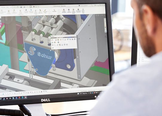 Mand sidder og kigger på et design af maskine på computer