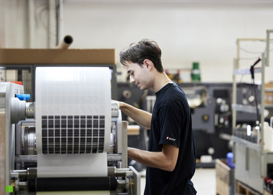 Mand står ved labelmaskine