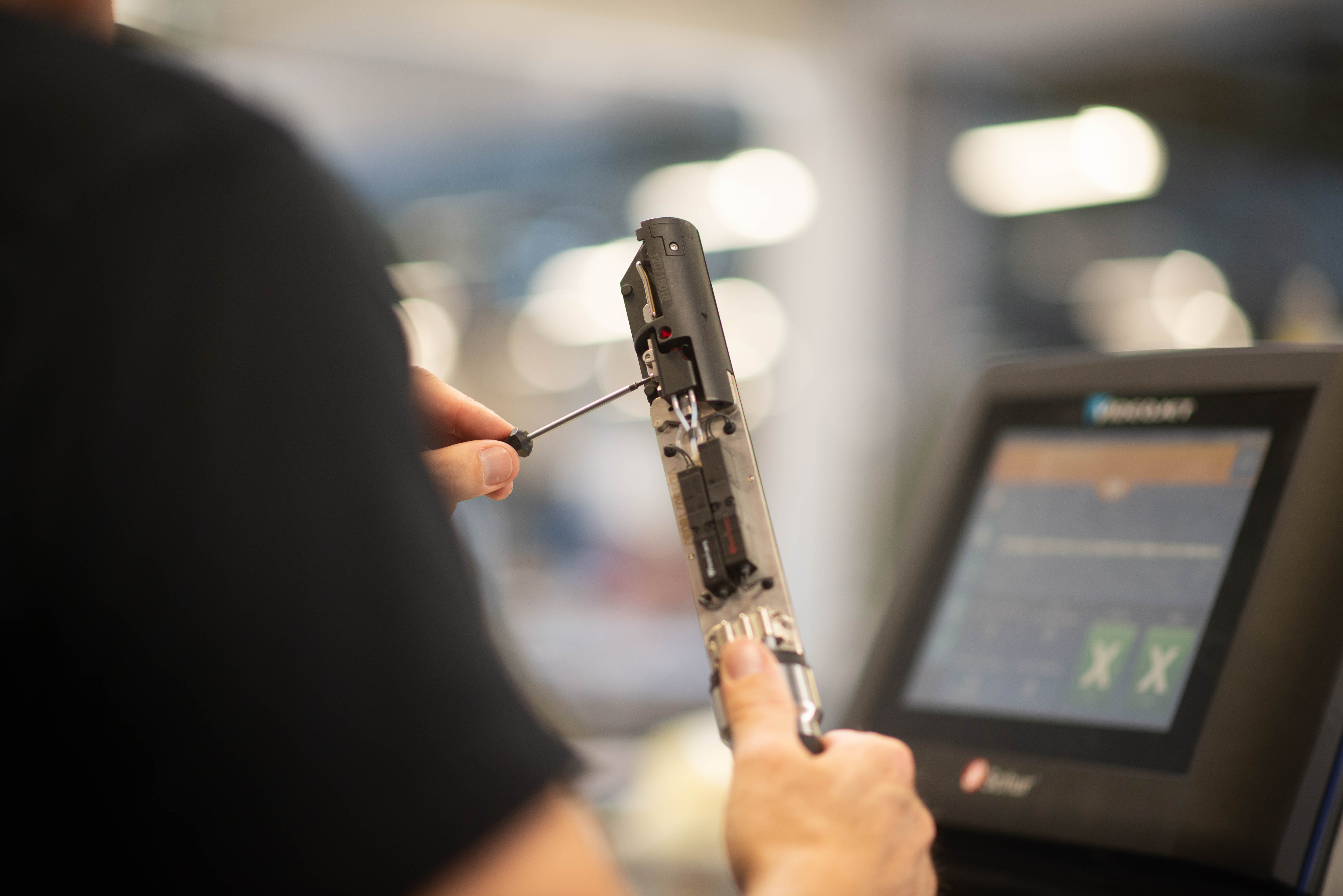 Mand der sidder med en skruetrækker og servicerer et produkt/maskine